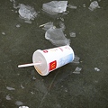 池の氷の上のマクドナルドのカップ