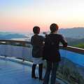 写真: 展望台から瀬戸の夕日を撮る若い二人連れ