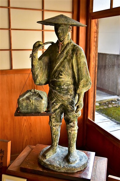 写真: 天秤棒を担いだ近江商人の像
